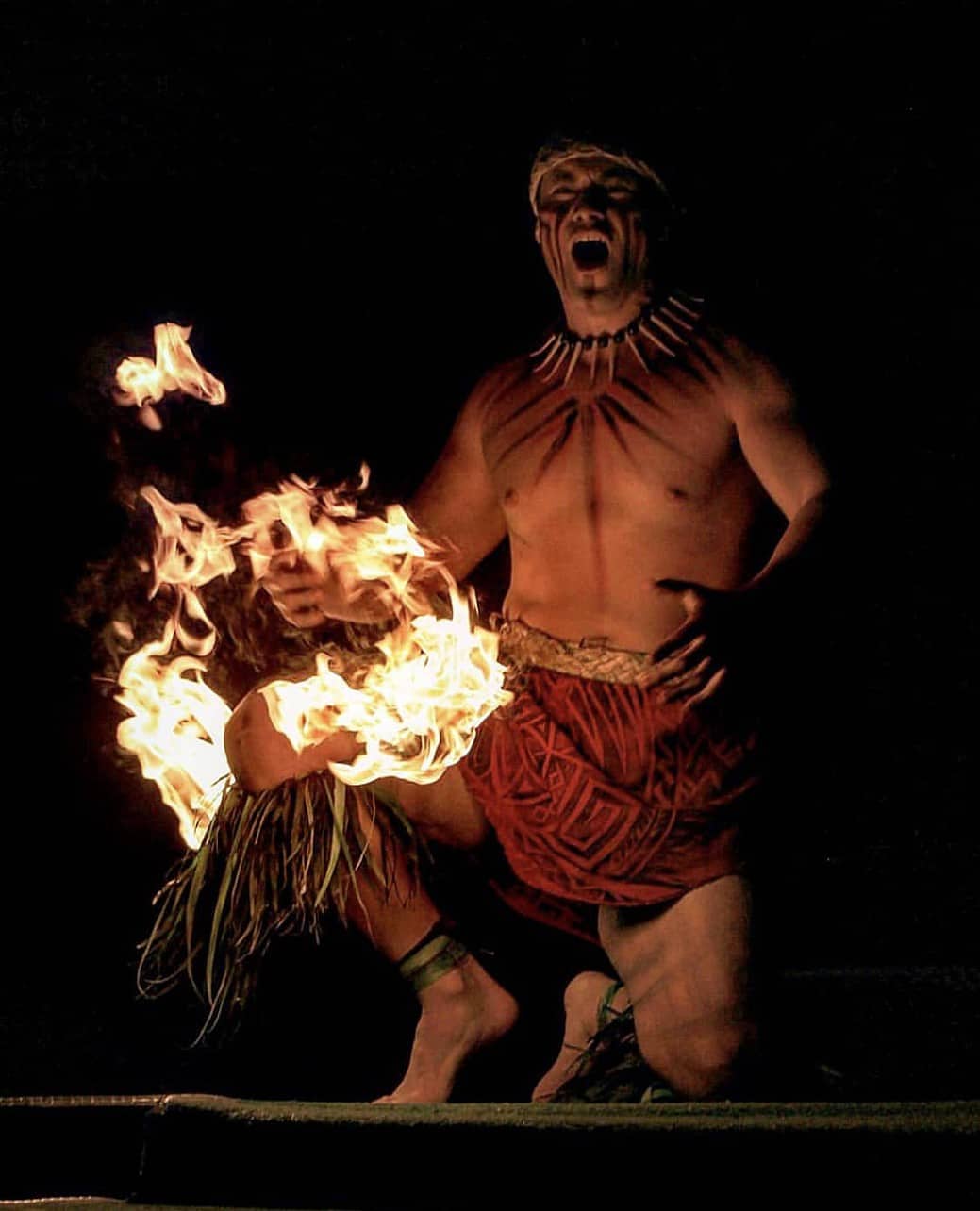 Samoan fire dancer kneeing at Paradise Cove Luau in O'ahu, Hawaii