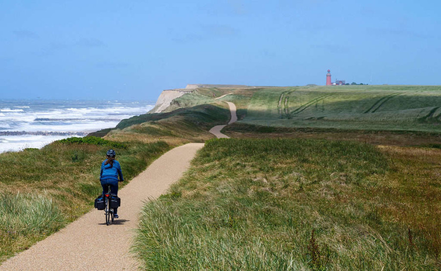 Cycling along the coast with Lodbjerg Lighthouse in the background, Denmark's West Coast.